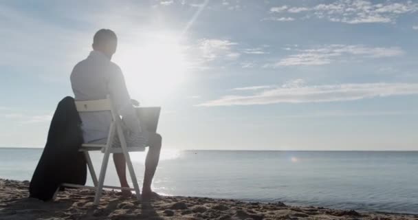 Businessman opens laptop and types sitting on wooden chair — Stock Video