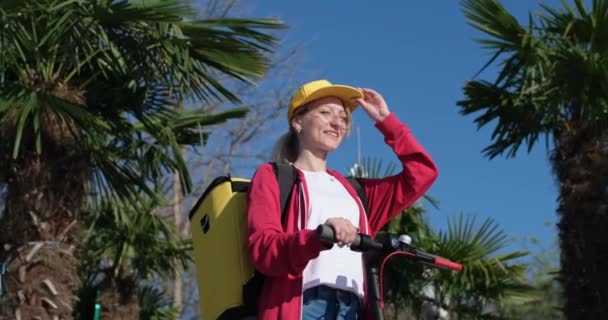 Blondine mit gelbem Liefersack fixiert gelbe Mütze — Stockvideo