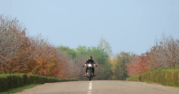 Młoda kobieta motocyklista w czarnym kasku jeździ na motocyklu — Wideo stockowe
