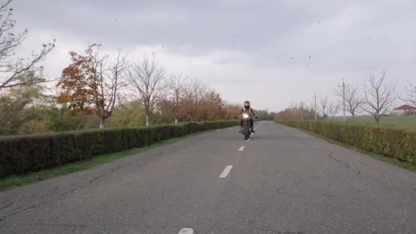 Młoda kobieta blondynka rowerzysta z długimi włosami jeździ motocyklem — Wideo stockowe