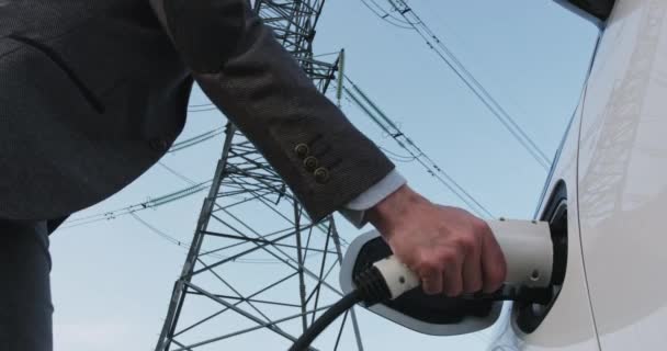 El hombre toma cable de carga de electromóvil en las líneas de la torre — Vídeo de stock