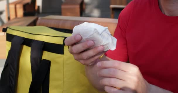 Muž vytahuje čerstvý burger ze značkového termobagu v kavárně — Stock video