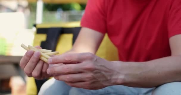 L'uomo mangia gustose patatine fritte e salviette mani nel caffè — Video Stock