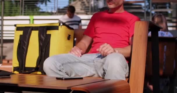 Deliveryman läser sms väntar på beställning på café terrass — Stockvideo