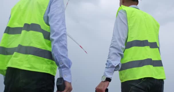 Ingenieros con equipo de radio y kit de herramientas miran la turbina eólica — Vídeo de stock