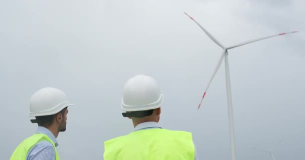 Ingenieure in Weißhelmen schauen sich den Betrieb von Windkraftanlagen an — Stockvideo