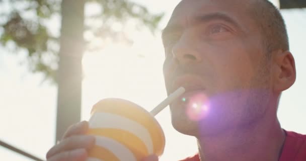 Az ember szalmával issza a poharat a napsütéses napon. — Stock videók