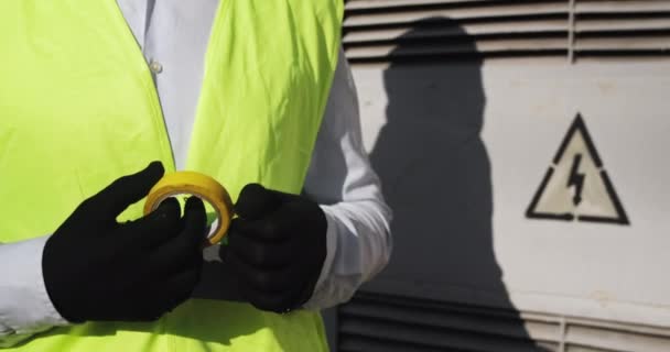 L'homme dévoile du ruban adhésif à proximité de la sous-station électrique — Video