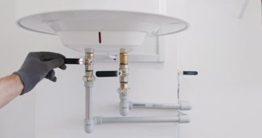 Isıtıcı vanalarının altına ve boruların altına monte edilmiş teknisyenler. Tesisat testleri kapatma işlevi, ısıtma sezonu başlamadan önce eklemleri doğrulamak için soğuk hat açar.