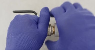 Mavi eldivenli eller vana gövdesinde sendika fındığı dönen konnektörünü kavrıyor. Tesisatçı denetleme için eklem vidalarını söker ve conta bütünlüğünü doğrulayan ip perdesini kontrol eder