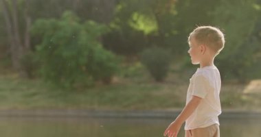 Anaokulu çocuğu oltaya takılan küçük oyuncak balıkları yakalamaya çalışıyor. Küçük sarışın çocuk çizginin sonunda sallanan renkli oyuncak balığını yakalamaya çalışıyor.