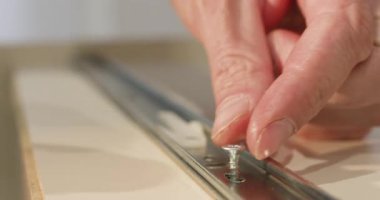 Adam sürgülü çekmece sistemine vida yerleştiriyor ve tornavida kullanarak sıkılaştırıyor. Kontrollü hareket, doğru hizalamanın yanı sıra güvenilir bir saptama sağlar