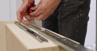 Adam yenileme sırasında şerit kullanarak kayan çekmece sistemini ölçüyor. Doğru boyutlar düzgün kurulum ve uzun ömürlü mobilya performansı sağlar