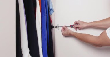 İnsan elleri mobilya tamiri sırasında manuel tornavida kullanarak dolap kapaklarını vidalayabilir. Kontrollü hareketler doğruluğu ve ev gelişimini yansıtır