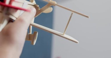 Aktif çocuk eli, oyun odasındaki açık alanda küçük tahta bir uçağı hareket ettirir. Mutlu çocuk ev yapımı kontrplak üreticisinden yapılmış vintage uçakla oynuyor.