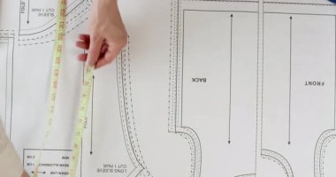 Profesyonel kadın terzi düzenli olarak şablon detaylarını mezurayla ölçer. Kılı kırk yaran kadın terzisi genişliği ve desen parçalarının yüksekliğini kontrol eder