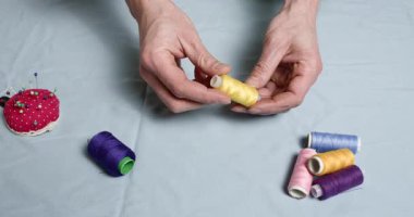 Profesyonel bir terzi parlak renkli ipliklerin makaralarını dikkatle inceler. Tecrübeli bir zanaatkar dikmek için en uygun tonları seçer.