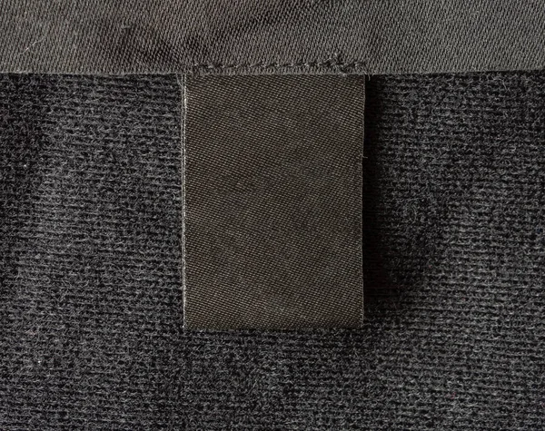 Leere Schwarze Wäscheetiketten Auf Schwarzem Textilhintergrund — Stockfoto