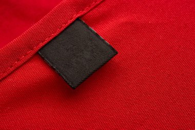 Blank black laundry care clothes label on red fabric texture background clipart