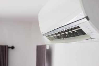 Beyaz duvar odasının arka planında klima var.