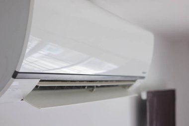 Beyaz duvar odasının arka planında klima var.