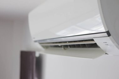 Beyaz duvar odasının arka planında klima var.