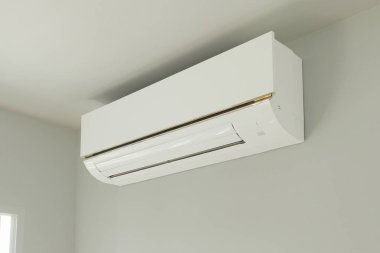 Beyaz duvar odasının arka planında klima var.
