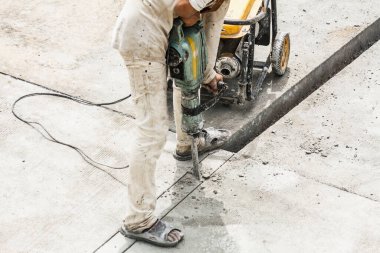 İnşaat işçisi beton sondaj yüzeyi kullanıyor.