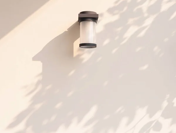 Outdoor cylinder lamp with tree leaves shadow on concrete wall