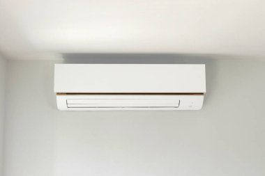 Beyaz duvar odasının arka planında klima var.