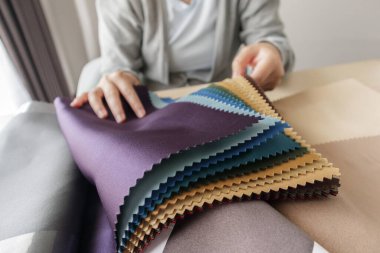 Kumaş rengi örnekleri olan kadın tasarımcı perde için tekstil seçiyor