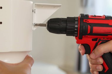 Beyaz masa mobilyalarını kablosuz tornavida kullanarak evde monte eden adam.