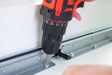 Beyaz masa mobilyalarını kablosuz tornavida kullanarak evde monte eden adam.