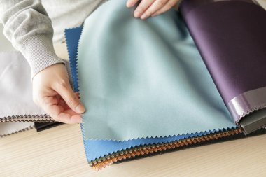 Kumaş rengi örnekleri olan kadın tasarımcı perde için tekstil seçiyor