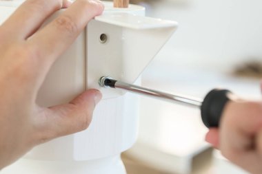 Asyalı adam beyaz masa mobilyalarını evde monte ediyor.