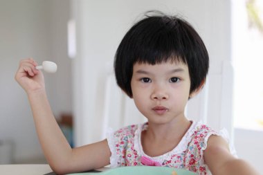 Küçük Asyalı kız kahvaltı yapıyor.