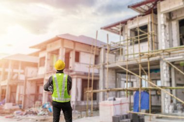 İnşaat şantiyesindeki koruyucu miğfer ve planlar üzerinde çalışan genç profesyonel mühendis.