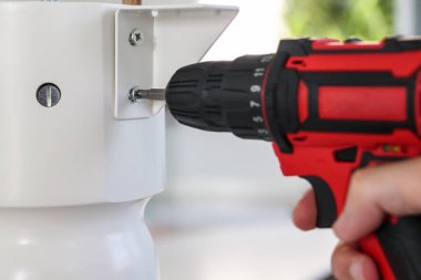 Beyaz masa mobilyalarını kablosuz tornavida kullanarak evde monte eden adam.