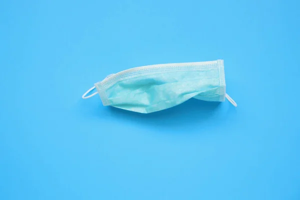 Disposable surgical face mask on blue background protection against COVID-19 coronavirus. Healthcare and medical concept