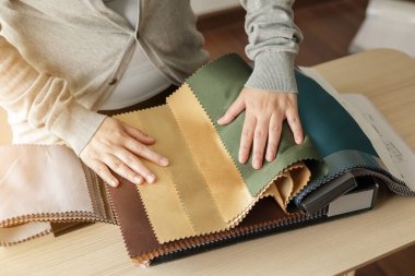 Kumaş rengi örnekleri olan kadın tasarımcı perde için tekstil seçiyor