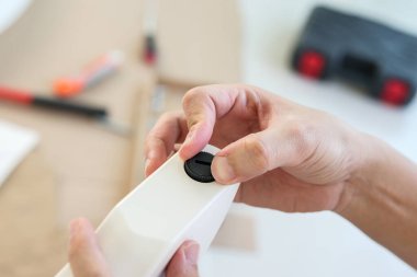 Asyalı adam, ayarlanabilir masa bacağıyla evde mobilya montajı yapıyor.