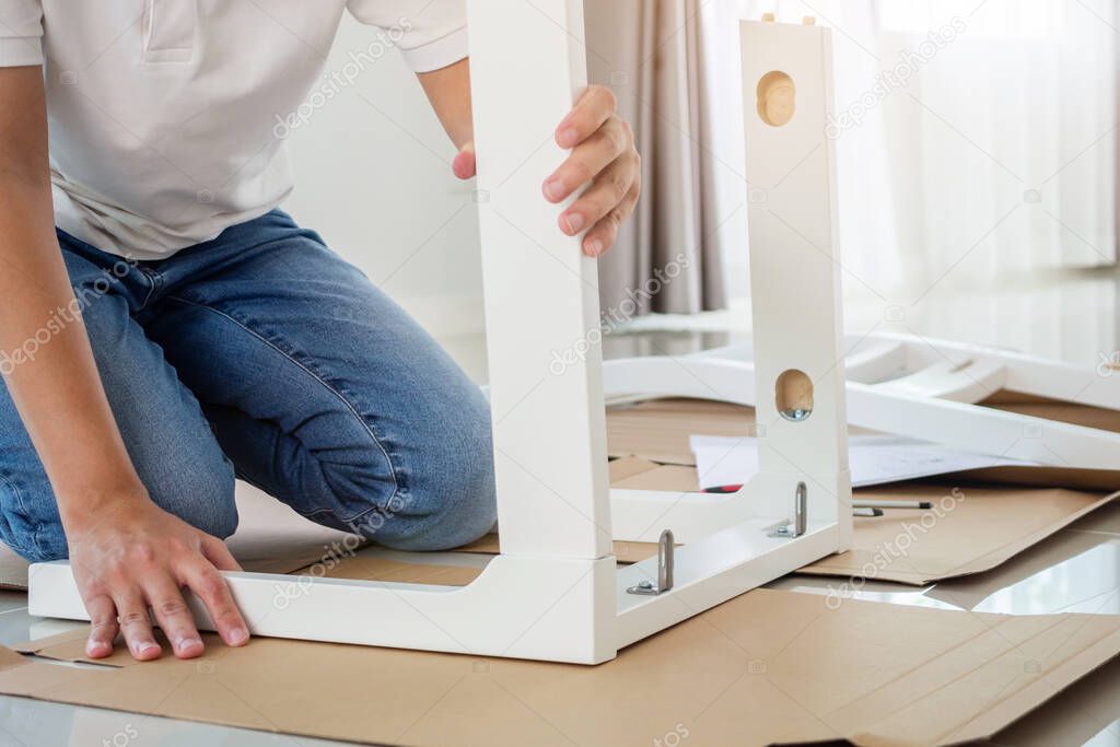 Man assembling white chair furniture at home