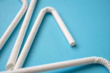 Biyo-çözünebilir çevre dostu beyaz kağıt mavi arka planda saman içiyor