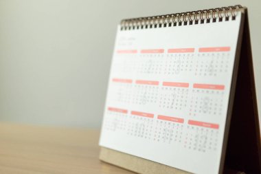 Takvim sayfası beyaz duvar arkası iş görüşmesi konseptiyle ahşap masaya yakın.