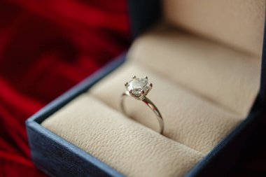 Kırmızı kumaş arka planda mücevher hediye kutusunda elmas yüzük.