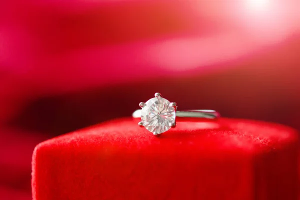 Diamond ring with jewelry gift box on red fabric background