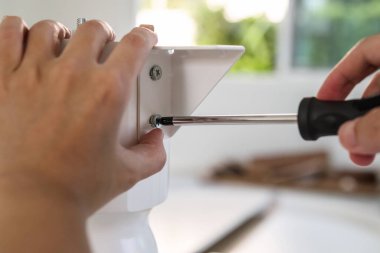 Asyalı adam beyaz masa mobilyalarını evde monte ediyor.