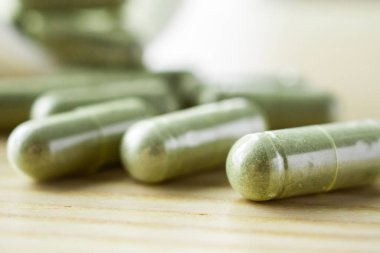 Ahşap masasında şişe bulunan bitkisel ilaç kapsülleri.