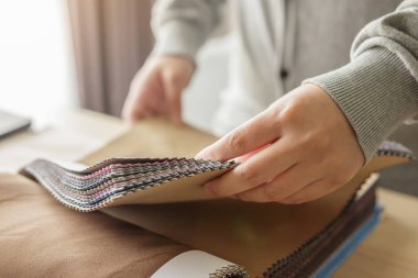 Kumaş rengi örnekleri olan kadın tasarımcı perde için tekstil seçiyor