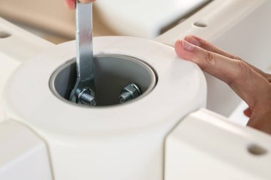 Asyalı adam beyaz masa mobilyalarını evde monte ediyor.